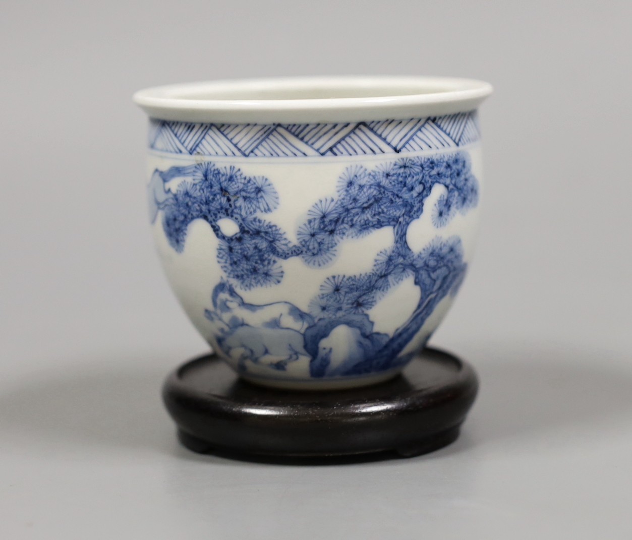 A Chinese blue and white ‘eight horses’ brush pot, on wooden stand, 8cm tall including stand